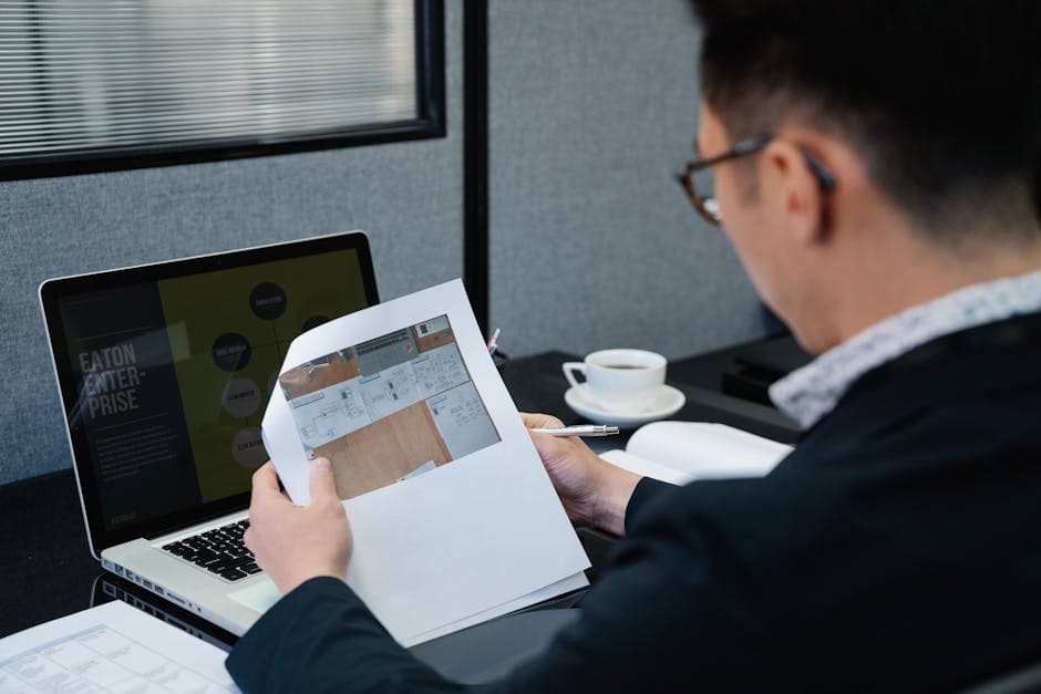 Professional reviewing documents on a laptop in an office