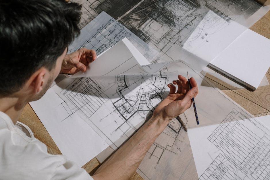 Estimator measuring and marking up construction drawings at a desk
